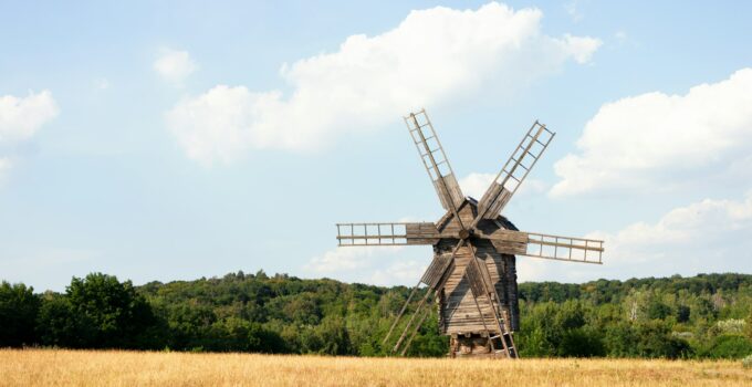 History windmill landscape rural scene. Blue sky, green trees and yellow field